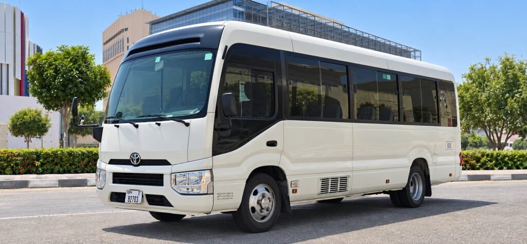 Front three-quarter view of a white Toyota Coaster minibus in Dubai