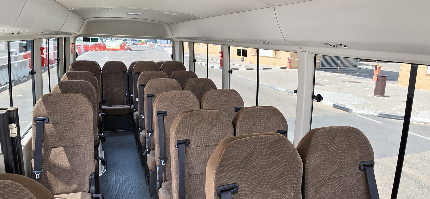 Toyota Coaster interior with rows of brown passenger seats and seat belts