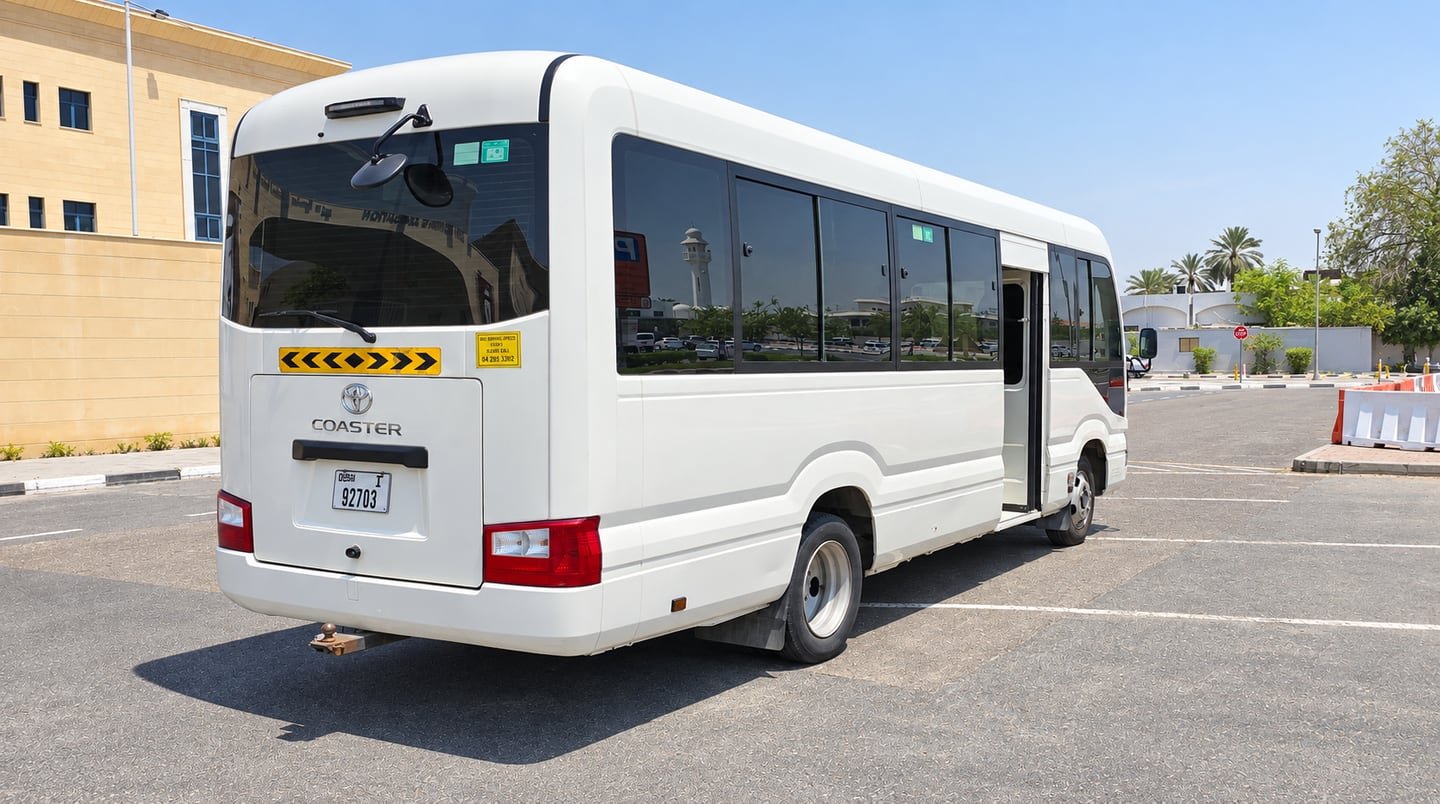 Rear three-quarter view of a white Toyota Coaster minibus